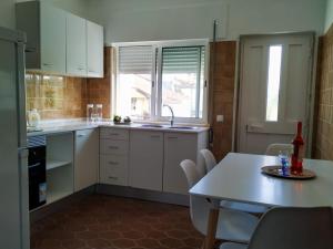 a kitchen with white cabinets and a table and a window at Casa Vaz in Grândola +16 photos