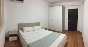 a bedroom with a white bed and a black door at Apartments Dione in Pomorie