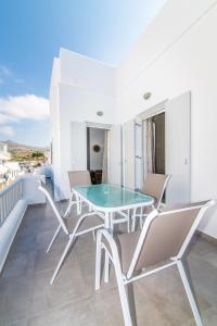 a dining room with a glass table and chairs on a balcony at Lux 'n Comfort Apartments in Tinos