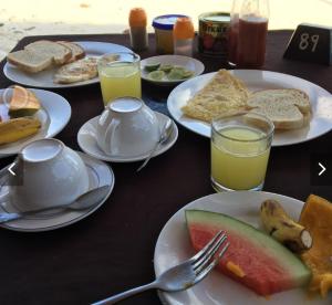 stół z talerzami jedzenia i szklanki soku pomarańczowego w obiekcie Ebony & Ivory Beach Bungalows w mieście Nungwi