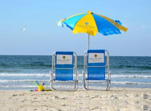 2 sillas de playa y 1 sombrilla en la playa en Residencial Vila do Sol, Apartamentos com pé na areia, en Bombinhas