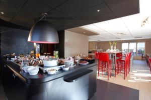 un restaurante con comida en una barra con sillas rojas en Campanile Dijon Sud - Marsannay en Marsannay-la-Côte