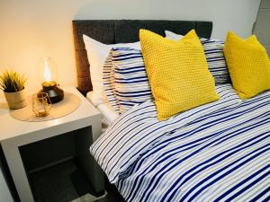 a bed with yellow and blue pillows and a night stand at Beautiful Brand New Apartment near the BEACH in Bournemouth