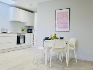 a white kitchen with a dining room table and chairs at Beautiful Brand New Apartment near the BEACH in Bournemouth