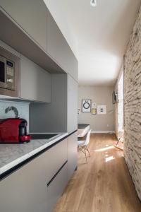 cocina con armarios blancos y pared de piedra en APARTAMENTOS ELEVEN ROOMS, en Burgos
