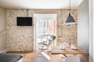 sala de estar con mesa y pared de piedra en APARTAMENTOS ELEVEN ROOMS, en Burgos