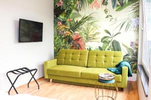a living room with a green couch and a mural at Das Fischer Boardinghouse in Bad Wörishofen