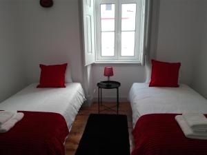 two beds with red pillows in a room with a window at Casa Joana B&B in Cascais
