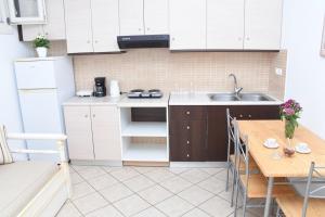 a kitchen with white cabinets and a wooden table at Little Yard Studios & Apartments #3 in Naxos Chora +10 photos