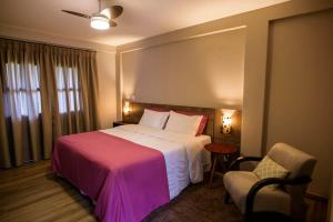 a hotel room with a large bed and a chair at Flor de Café Pousada in Pedra Menina