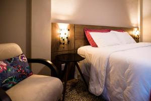 a hotel room with a bed and a chair at Flor de Café Pousada in Pedra Menina