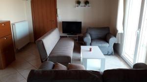 a living room with a couch and chairs and a tv at HOUSE DILENA TSIMTSIRI in Limenaria