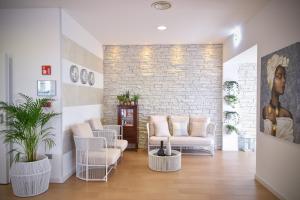 sala de estar con muebles blancos y pared de ladrillo en Hotel Lux, en Caorle
