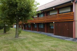 a red building with a tree in front of it at Campanile Lille Sud - Douai Cuincy in Cuincy