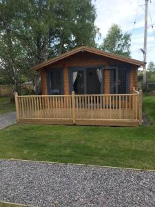 a small cabin with a fence and a porch at Star Cabin Lairg in Lairg