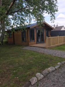 a small wooden house with a porch and a yard at Star Cabin Lairg in Lairg