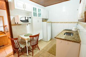 cocina pequeña con mesa pequeña y microondas en VHL Apartamentos, en Campos do Jordão