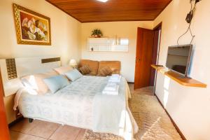 1 dormitorio pequeño con 1 cama y TV en VHL Apartamentos, en Campos do Jordão