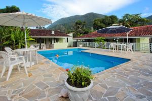 a pool with a table and chairs and an umbrella at CASA TEMPORADA TUCO E TUCA in Ubatuba