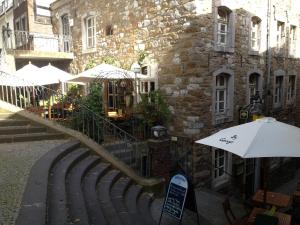 a restaurant with tables and umbrellas in front of a building at Gästehaus By George in Stolberg