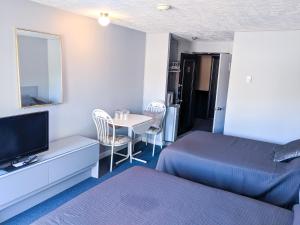 1 dormitorio con 1 cama y 1 mesa con TV en Skyline Motel, en Fredericton