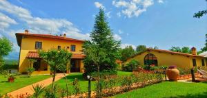 una casa amarilla con un jardín delante de ella en Torrebianca Tuscany, en Rignano sullʼArno