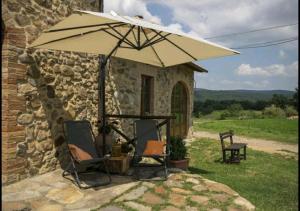 a patio with two chairs and an umbrella at Casetta della Pina in Monticiano