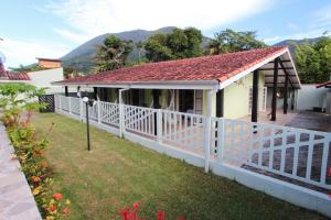 a house with a white fence and mountains in the background at CASA TEMPORADA TUCO E TUCA in Ubatuba