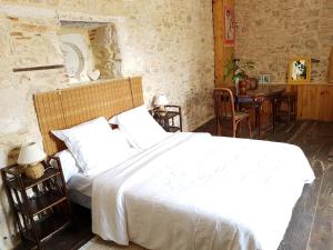 a bedroom with a large white bed and a table at Le Nid des Oiseaux in Cubjac