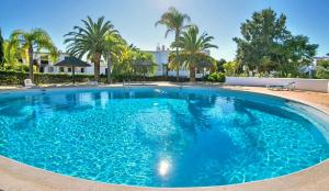 una grande piscina blu con palme e una casa di CASA ELISA SAO RAFAEL ad Albufeira