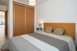 a bedroom with a large bed with a wooden headboard at AL Cabanas de Tavira in Cabanas de Tavira