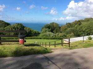 a trash can sitting next to a fence at 19 Chalet Bucklands , Bideford Holiday Park. in Bucks Mills