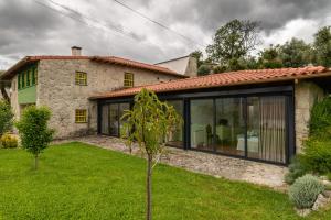 a house with large glass doors and a yard at Eido Da Portela - Casa De Campo in Carregadouro