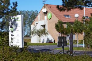 una señal frente a una casa con un edificio en Campanile Dunkerque Sud - Loon Plage en Loon-Plage