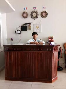 un hombre sentado en un mostrador en una habitación en TWIN HOME Guesthouse en Kampot