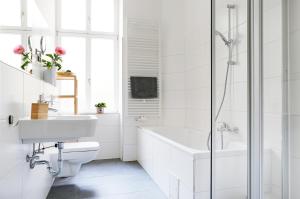 a white bathroom with a tub and a sink at Be in Berlin Apartments in Prenzlauer Berg in Berlin