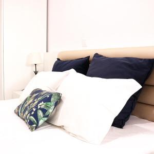 a bed with white sheets and blue pillows at Avenida in Praia de Mira