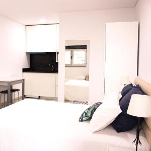 una camera da letto con pareti bianche e un letto con specchio di Avenida a Praia de Mira