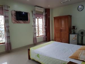 een slaapkamer met een bed en een tv aan de muur bij Khách sạn Anh Đào in Phủ Lý