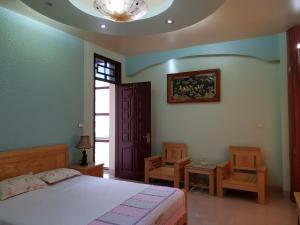 een slaapkamer met een bed en 2 stoelen en een plafond bij Khách sạn Anh Đào in Phủ Lý