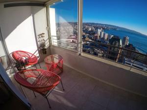 balcón con sillas rojas y vistas a la ciudad en Departamentos Alto Libertad, en Viña del Mar