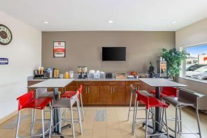 eine Küche mit 2 Tischen und eine Bar mit roten Stühlen in der Unterkunft Econo Lodge Baton Rouge University Area in Baton Rouge