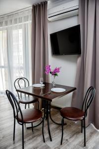 a dining room table with chairs and a tv on a wall at Apart Reserve Sloboda Loft in Ivano-Frankivsʼk