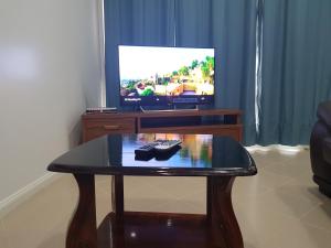 a coffee table in front of a tv with a remote control at Prestige Apartments - Solomon Islands in Honiara