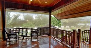 a screened in porch with two chairs and a table at Bed & Breakfast Chiang Rai in Ban Du