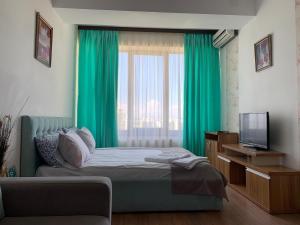 ママイアにあるCazari Mamaia Summerlandのベッドルーム(緑色のカーテン、テレビ付)