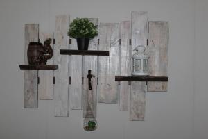 a wall with two shelves with a candle and a plant at Windrose in Liepāja