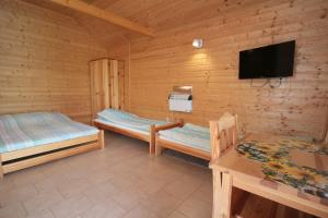 a room with two beds and a flat screen tv at Domki w Ogrodzie in Stegna
