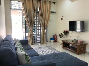 salon z niebieską kanapą i telewizorem w obiekcie Magnolia 1 Homestay w mieście Kuala Besut