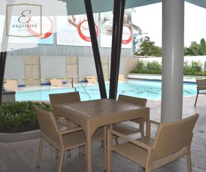 uma mesa e cadeiras ao lado de uma piscina em Aimee Exquisite Spaces em Iloilo